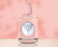 A clear pink refillable plastic fragrance pump spray bottle labeled COLOR CODE SCREW by Aptar, 50 ml, 80 ml sits on a reflective surface with a soft pink background.