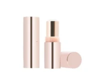 A light pink, cylindrical non guided mini lipstick packaging with a metallic accent is shown standing upright, with the cap removed and placed beside it, revealing the product inside against a white background.
