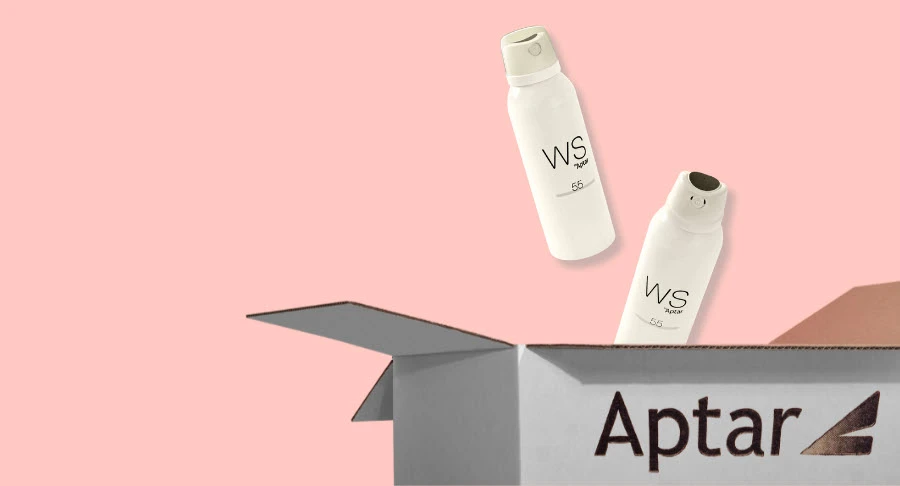 Two white spray bottles labeled WS, with Bicolor Aerosol Actuators, hover above an open cardboard box with the word Aptar printed on the side, set against a light pink background.