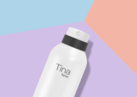 A white spray bottle labeled Tina Aptar, featuring a twist-to-lock aerosol actuator for spray, lies on a pastel geometric background with sections of purple, peach, and blue.