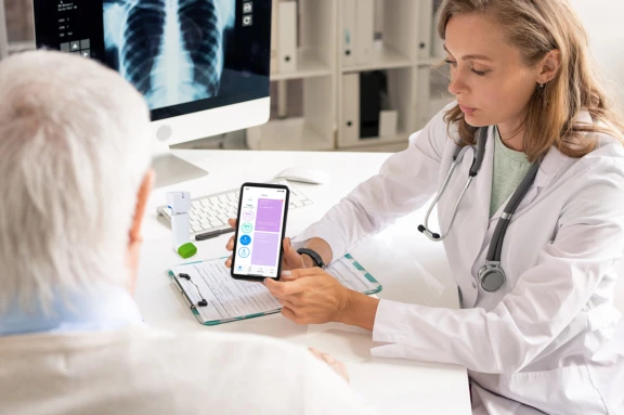 Doctor showing how to use HeroTracker Sense and Cohero BreatheSmart app to a patient
