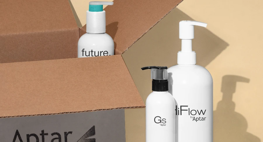 Three white bottles labeled Future, HiFlow, and GS, with GS showcasing Aptar Beauty's Iconic high-performing dispensing pump. Displayed beside an open cardboard box on a soft beige background.
