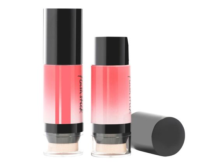 Two coral-colored face sticks with black caps and sponge applicators, one taller than the other, and a detached black cap on a white background.