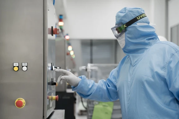 Aptar Pharma’s clean room operator in blue sterile gowning starting a robotized manufacturing process of sterile components.