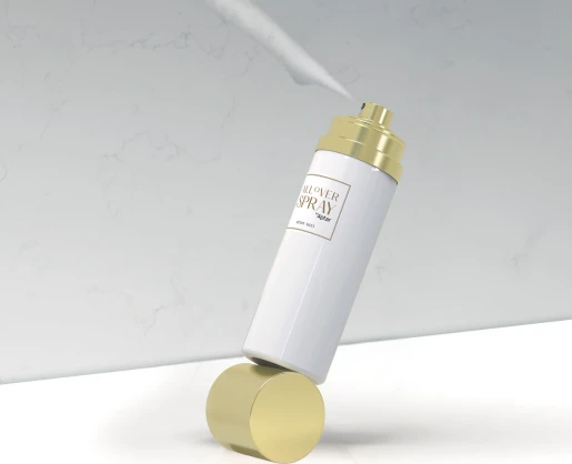 A white and gold bottle with premium aerosol packaging labeled All Over Spray is balanced at an angle on a gold cylindrical stand against a light, marble-patterned background with a spray pattern coming out of the actuator.