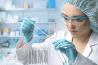 A young female scientist loads liquid sample into test tube with plastic pipette