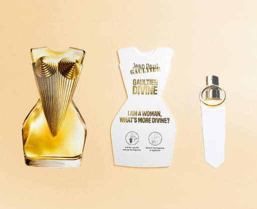 Stylized gold torso-shaped fragrance sample sampling with matching paper strip, illustrating Aptar Beauty's SCENTOUCH reusable paper fragrance solution for Jean Paul Gaultier's Divine scent.