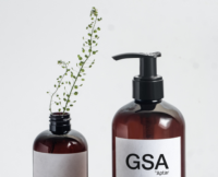 A brown bottle with Aptar Beauty's GSA dispensing pump with a metal-free pathway is displayed alongside green plantsin a bottle, emphasizing its eco-friendly and sustainable design