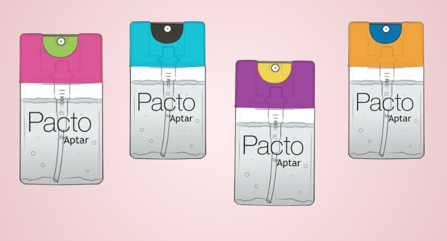 Four Purette Lotion  spray bottles with flat mini packaging are labeled 'Pacto by Aptar' are arranged side by side, each featuring a different colored top: pink, blue, orange, and purple , set against a light pink background.