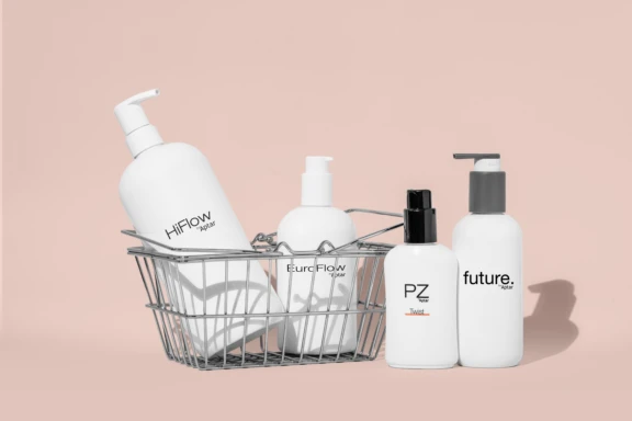 Four white high performance dispensing pump bottles labeled HiFlow, EuroFlow, PZ, and Future are arranged in and beside a small wire basket, set against a pale pink background.