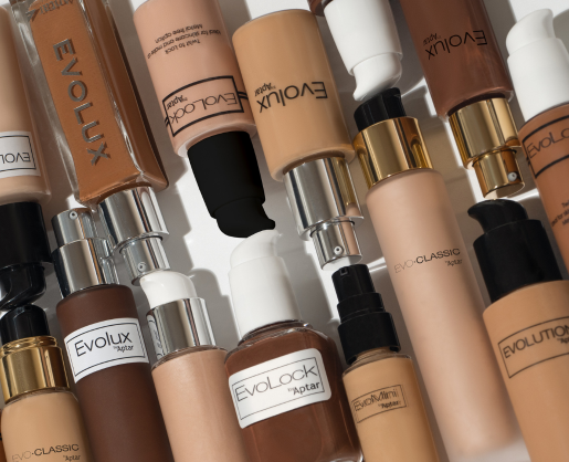 Several bottles of liquid foundation in various skin tones are arranged on a white surface. The Evolux, Evolock, and Evo-Classic bottles each feature a pump or twist-to-lock cosmetic pump for convenience and secure application.