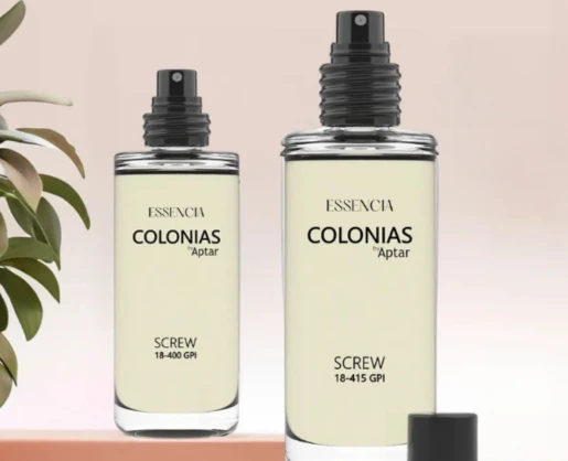 Two clear glass spray bottles labeled Essencia Colonias by Aptar offer a discreet refillable fragrance experience. The left bottle is labeled Screw 18-400 GPI, the right Screw 18-415 GPI, with a green plant partially visible on the left.
