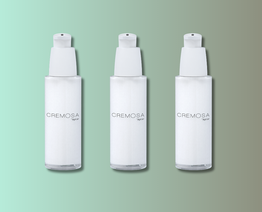 Three identical white elegant cosmetic pump bottles labeled CREMOSA are arranged in a row against a gradient green and beige background.