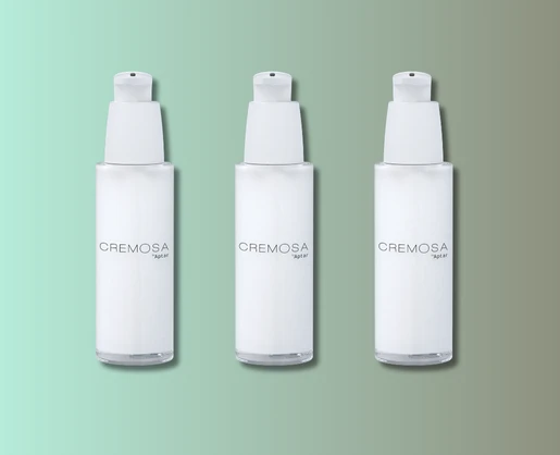 Three identical white elegant cosmetic pump bottles labeled CREMOSA are arranged in a row against a gradient green and beige background.