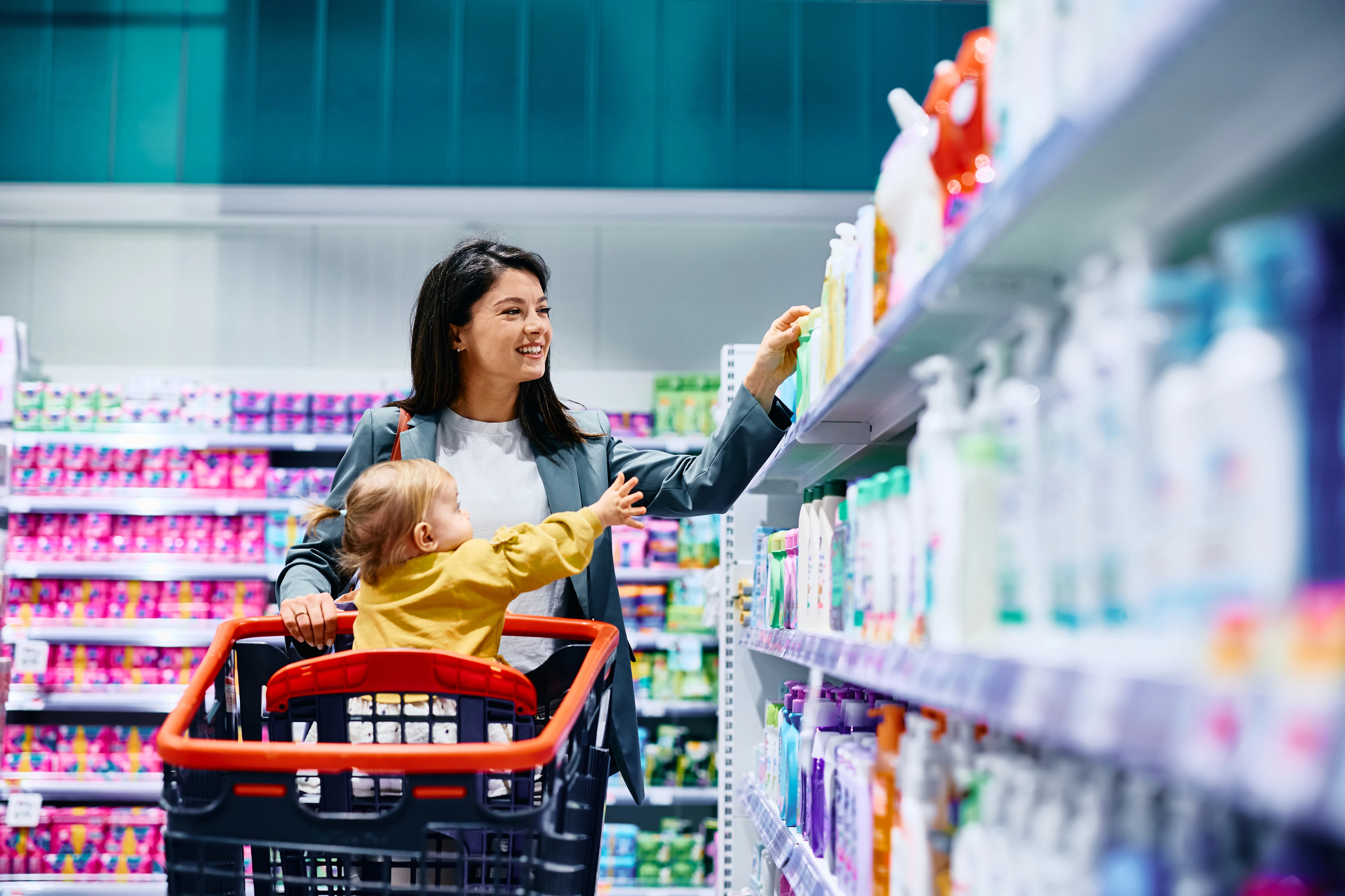 A mother and her baby shopping in the personal care section of the grocery store