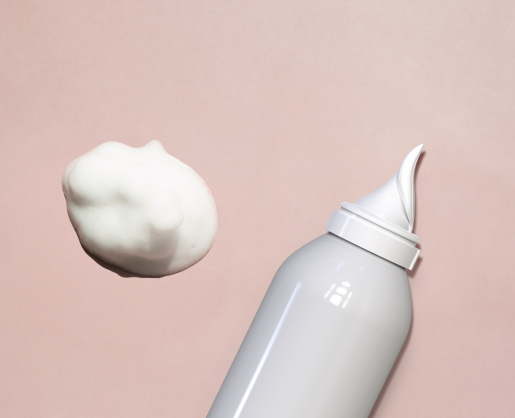 An aerosol actuator for whipped formulas named Aspire with a pointed nozzle dispenses a dollop of white foam against a soft pink background.